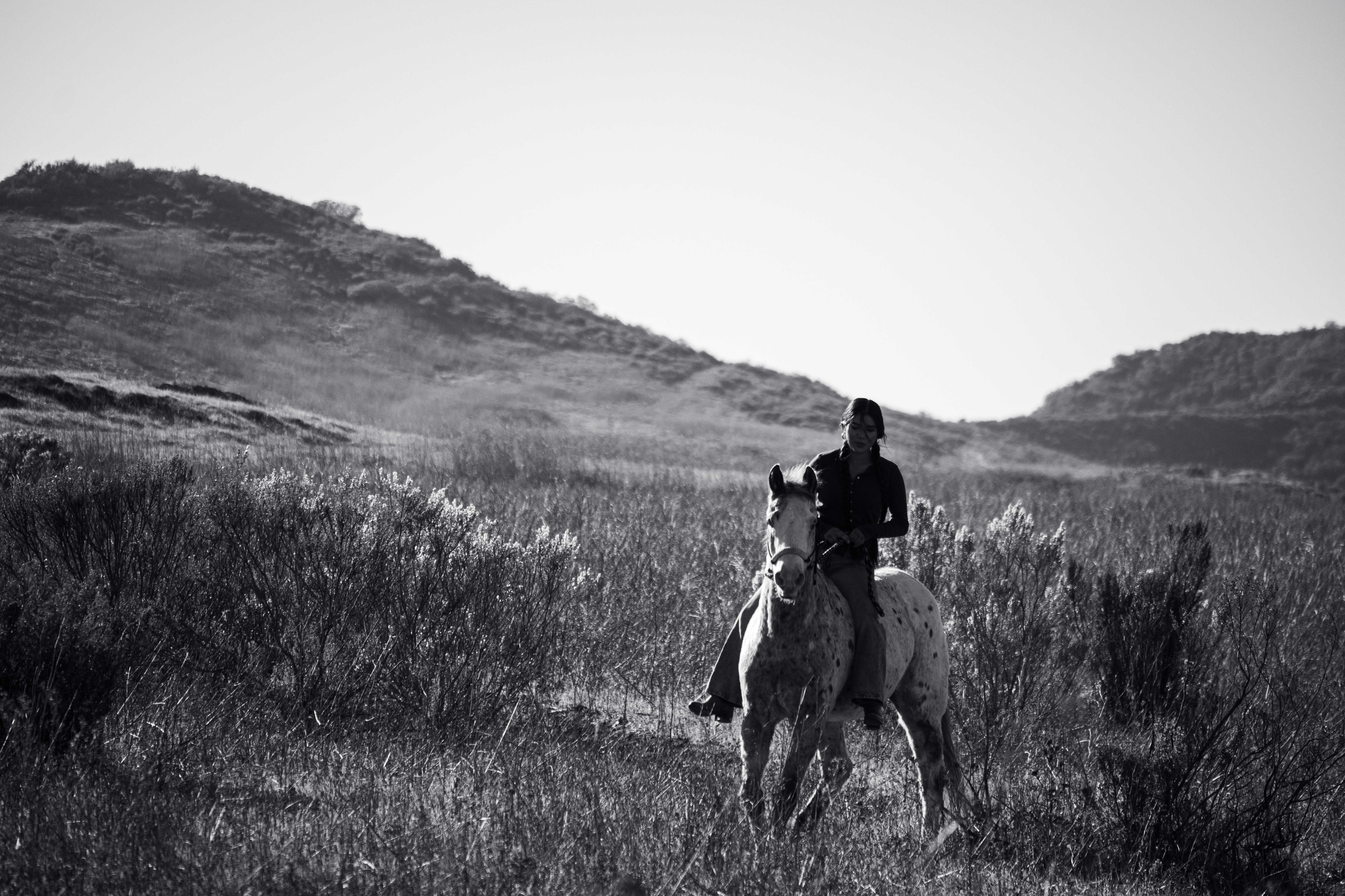 Anna and Pompy riding across the hills at Potrero Ranch, small in the frame